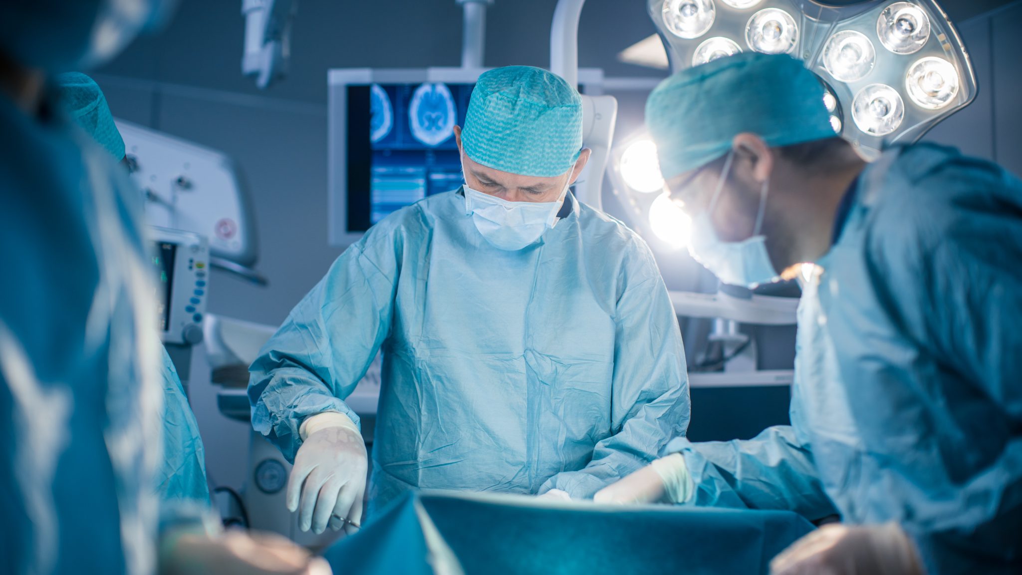 Diverse Team of Professional surgeon, Assistants and Nurses Performing Invasive Surgery on a Patient in the Hospital Operating Room. Surgeon Use Instruments. Real Modern Hospital with Authentic Equipment.